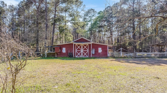 view of barn featuring a yard and fence