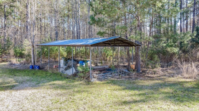 view of yard with a forest view, a carport, and driveway