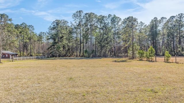 view of yard featuring fence and a forest view