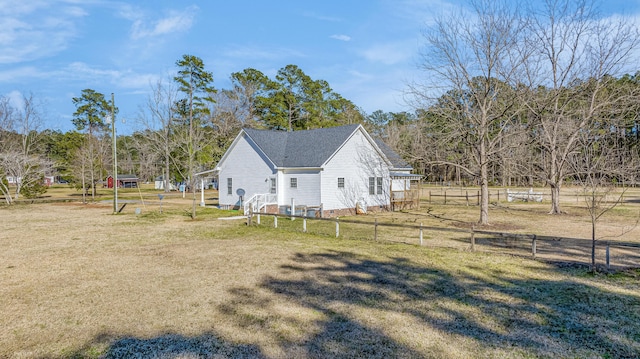 view of side of home with a lawn and fence