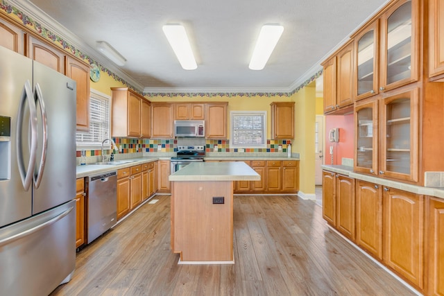 kitchen with light wood-style flooring, a sink, a center island, appliances with stainless steel finishes, and light countertops