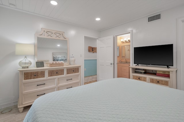 bedroom with light hardwood / wood-style floors, ensuite bathroom, and sink