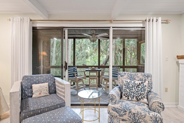 living area with a wealth of natural light, ceiling fan, beamed ceiling, and hardwood / wood-style floors