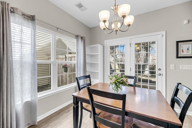 dining space featuring an inviting chandelier, light wood-style flooring, baseboards, and visible vents