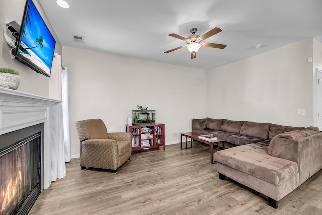 living area featuring a lit fireplace, visible vents, and light wood-style floors