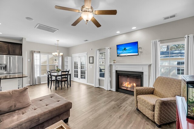 living area with light wood-style flooring, visible vents, and a wealth of natural light