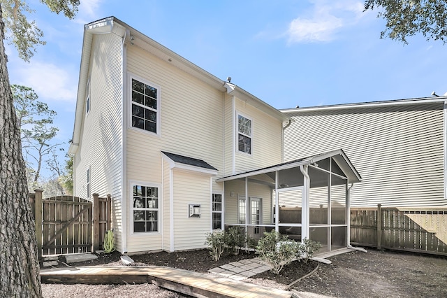 back of property featuring a sunroom, fence, and a gate