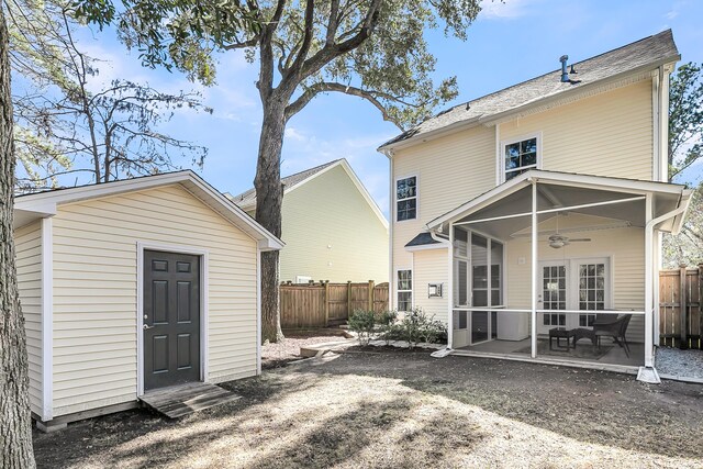 rear view of house with a ceiling fan, an outbuilding, a fenced backyard, and a sunroom