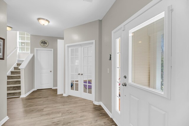 foyer entrance featuring stairway, baseboards, and light wood-style flooring