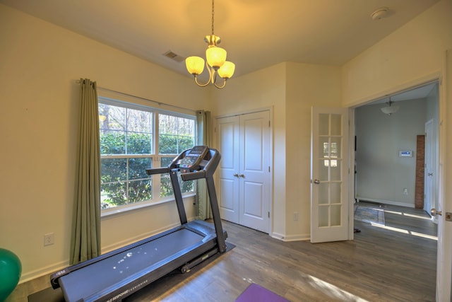 workout area featuring a chandelier, visible vents, baseboards, and wood finished floors