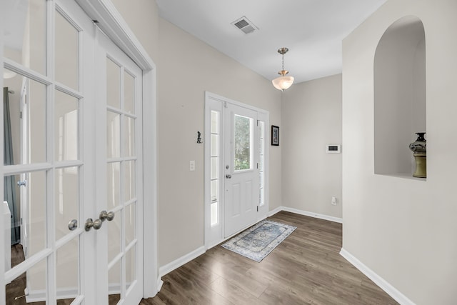 foyer entrance with visible vents, baseboards, french doors, wood finished floors, and arched walkways