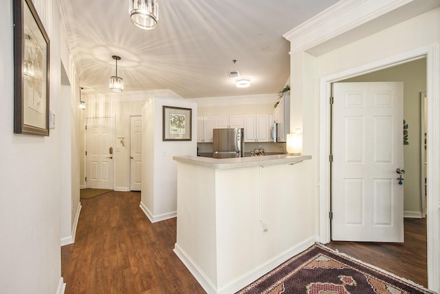 kitchen featuring light countertops, appliances with stainless steel finishes, ornamental molding, white cabinets, and a peninsula