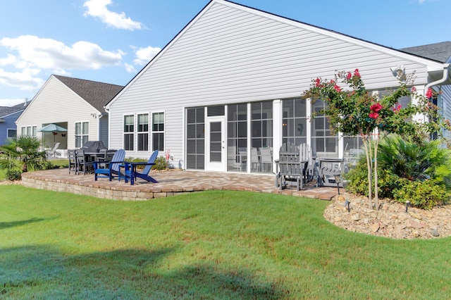 rear view of house featuring a sunroom, a lawn, and a patio