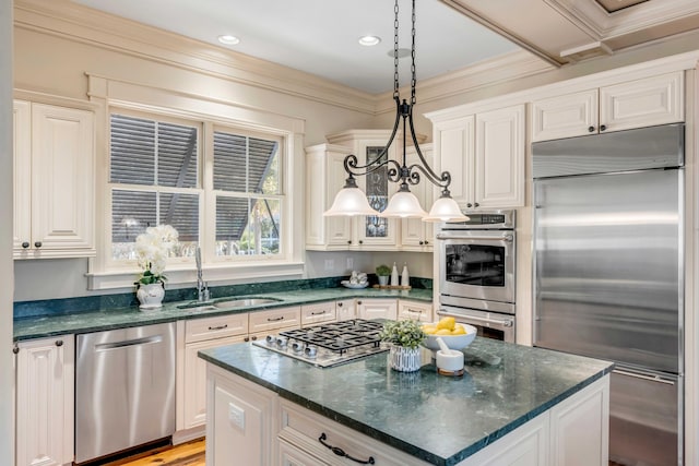 kitchen featuring sink, white cabinetry, stainless steel appliances, decorative light fixtures, and crown molding