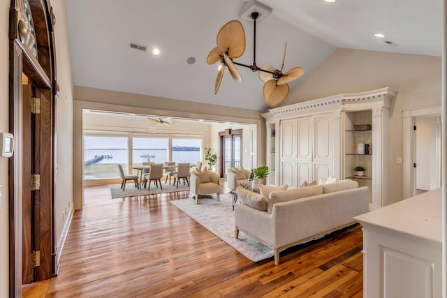 living room featuring a water view, high vaulted ceiling, and light hardwood / wood-style flooring