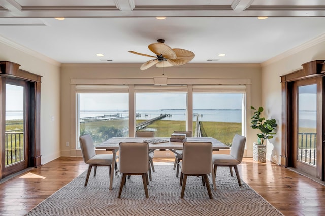 dining space with a water view, light hardwood / wood-style floors, a wealth of natural light, and ceiling fan