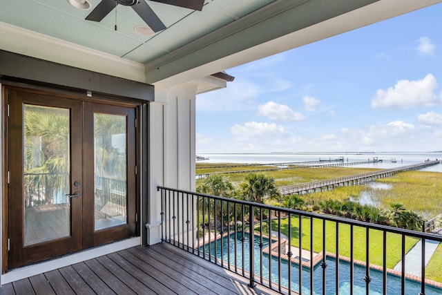 balcony with french doors, a water view, and ceiling fan