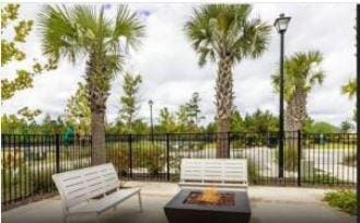 view of community with a patio area, a fire pit, and fence