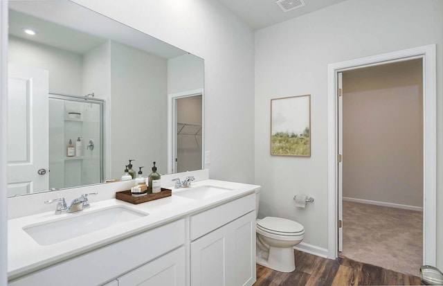 full bath featuring toilet, wood finished floors, a stall shower, and a sink