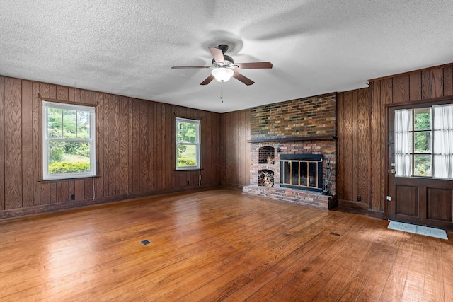 1019 Pinon Rd, North Augusta, SC 29841 - unfurnished living room featuring wood-type flooring, ceiling fan, healthy amount of natural light, a textured ceiling, and wooden walls