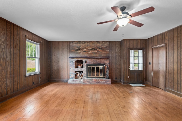 1019 Pinon Rd, North Augusta, SC 29841 - unfurnished living room featuring hardwood / wood-style floors, healthy amount of natural light, wood walls, and a fireplace