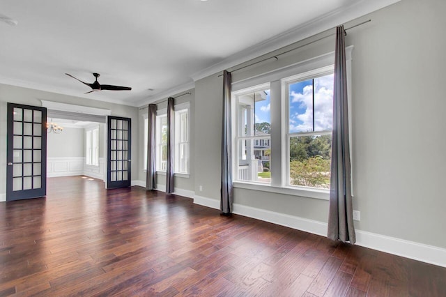 empty room with french doors, dark hardwood / wood-style floors, ceiling fan with notable chandelier, and ornamental molding