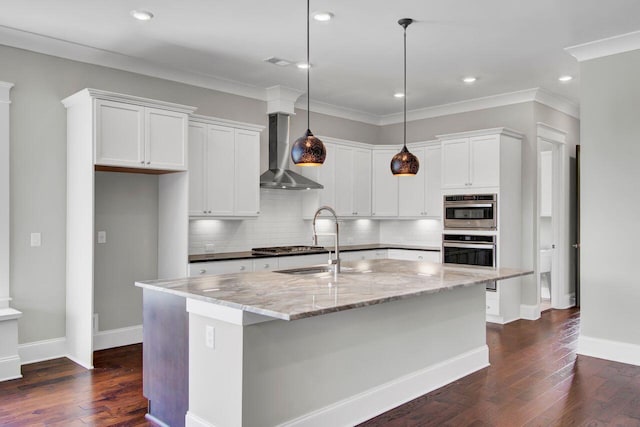 kitchen featuring light stone countertops, a center island with sink, white cabinetry, and wall chimney range hood