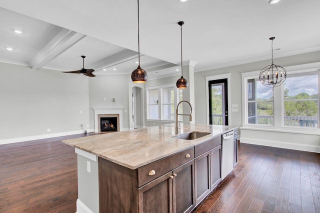 kitchen with pendant lighting, a center island with sink, sink, light stone countertops, and beam ceiling