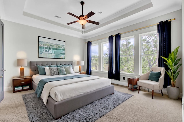 carpeted bedroom with a tray ceiling and ceiling fan