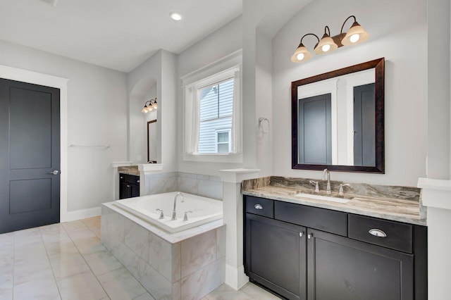 bathroom with vanity and tiled tub