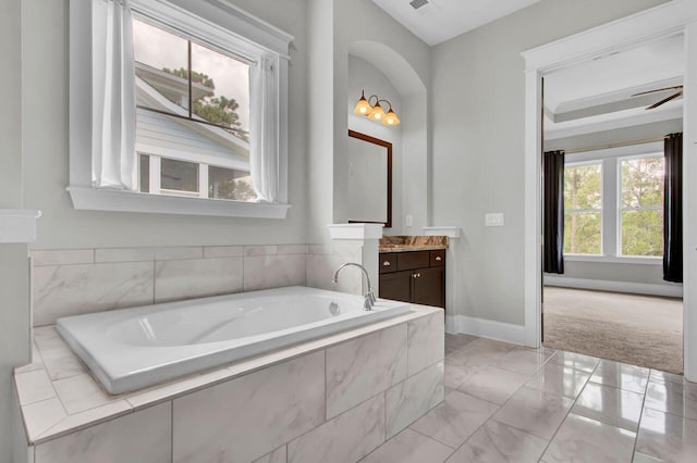 bathroom featuring vanity, a relaxing tiled tub, and ceiling fan