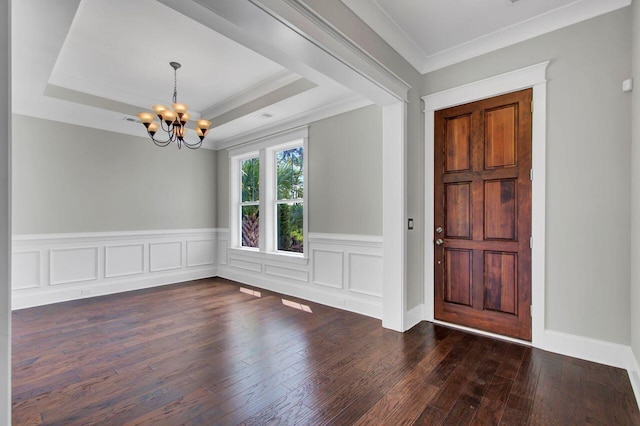 foyer entrance featuring a chandelier, a tray ceiling, dark wood-type flooring, and crown molding