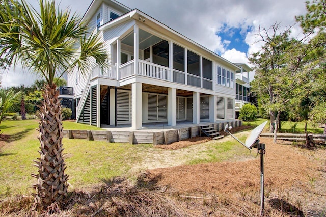 rear view of house featuring a lawn, a sunroom, and ceiling fan