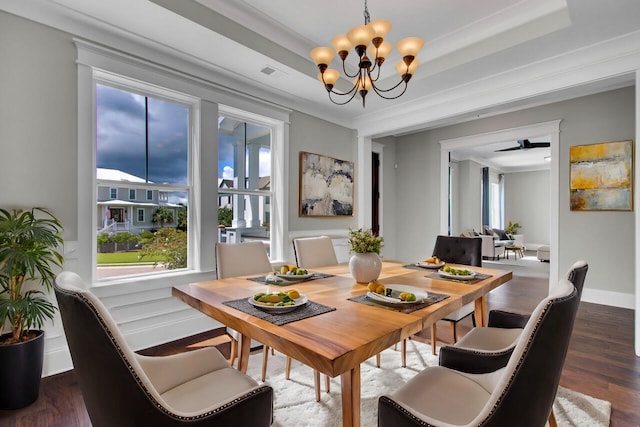 dining room with ceiling fan with notable chandelier, dark wood-type flooring, a raised ceiling, and crown molding