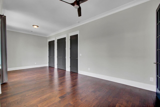 interior space with ceiling fan, dark hardwood / wood-style flooring, ornamental molding, and two closets