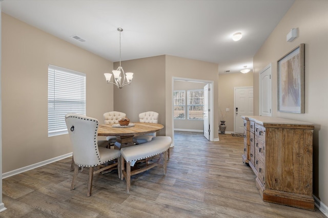 dining area featuring hardwood / wood-style flooring and an inviting chandelier