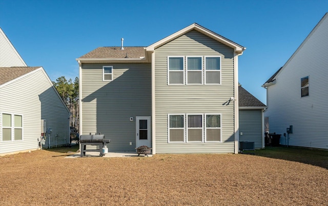 back of property with central AC unit, a patio, and a lawn