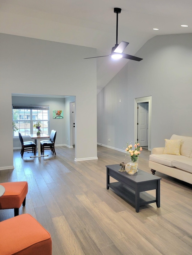 living room featuring high vaulted ceiling, light hardwood / wood-style flooring, and ceiling fan