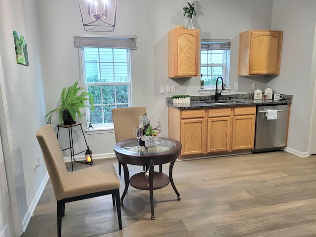 kitchen featuring dishwasher, sink, a notable chandelier, dark stone counters, and light hardwood / wood-style floors