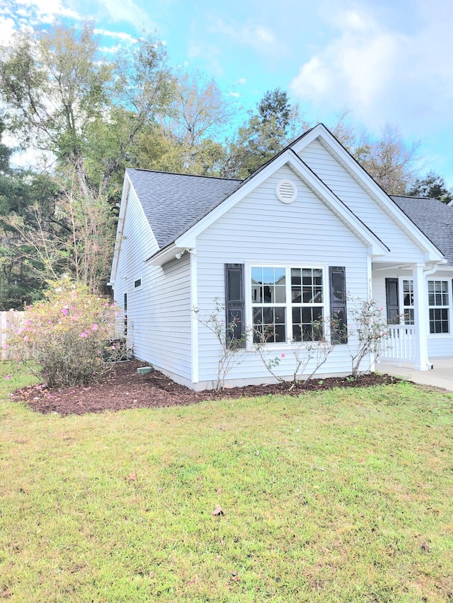 view of side of home with covered porch and a yard