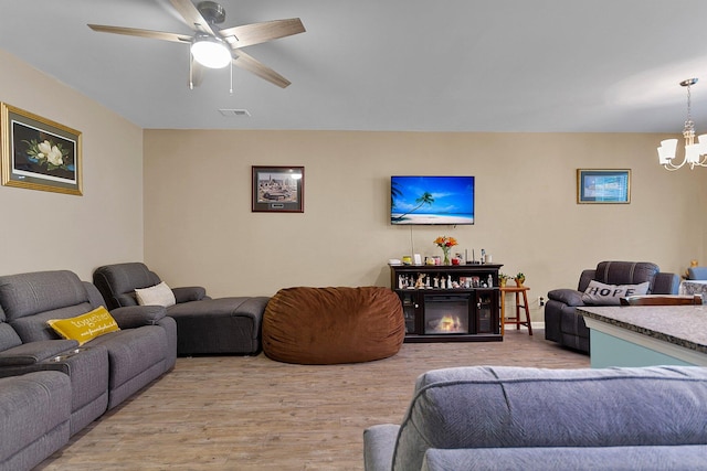 living room with ceiling fan with notable chandelier and hardwood / wood-style flooring