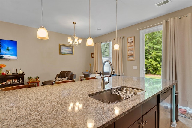 kitchen with a chandelier, decorative light fixtures, sink, and light stone countertops