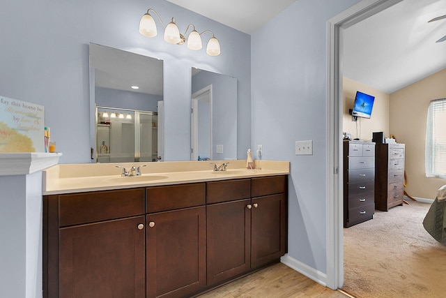 bathroom featuring dual sinks, wood-type flooring, vaulted ceiling, and large vanity