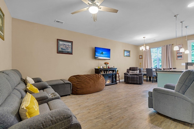 living room featuring ceiling fan with notable chandelier and hardwood / wood-style flooring