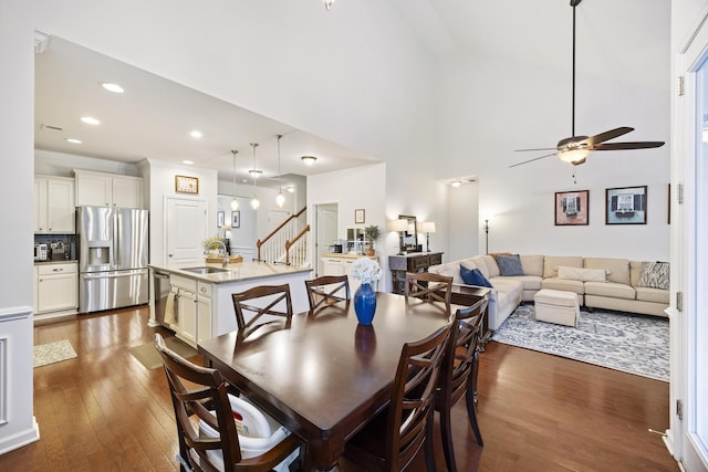 dining area featuring sink, ceiling fan, a towering ceiling, ornamental molding, and dark hardwood / wood-style flooring