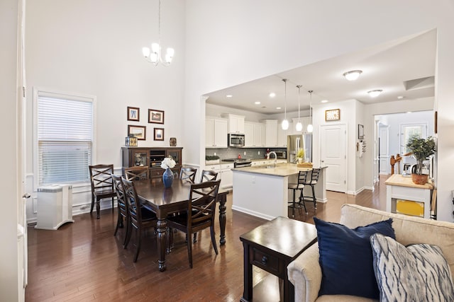 dining room featuring a high ceiling, a healthy amount of sunlight, dark hardwood / wood-style floors, and a notable chandelier