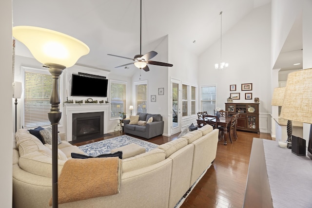 living room featuring plenty of natural light, dark hardwood / wood-style floors, ceiling fan with notable chandelier, and high vaulted ceiling