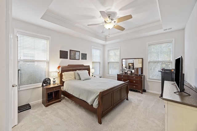 carpeted bedroom with ceiling fan, a raised ceiling, and ornamental molding