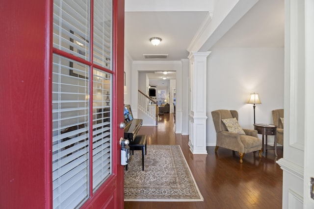 foyer entrance featuring decorative columns, dark hardwood / wood-style floors, and ornamental molding