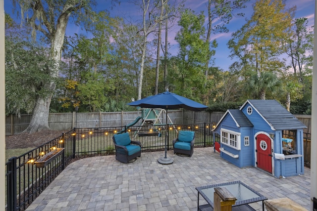 patio terrace at dusk with an outbuilding and a playground